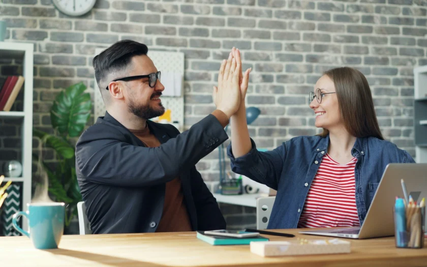 deux collègues qui se font un high-five au bureau, ambiance positive au travail