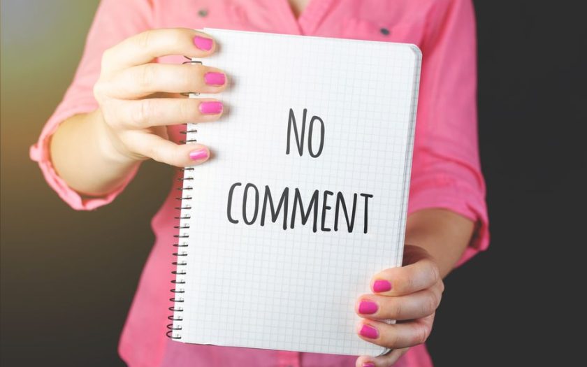 A woman in a pink shirt holds a notebook with 'No comment' text visible, conveying silence or privacy.