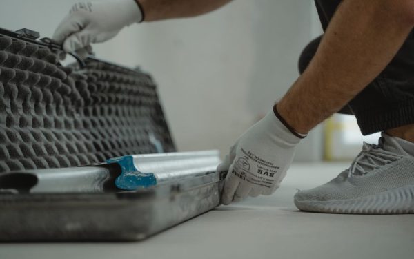 A construction worker organizing tools inside a toolbox on a job site.