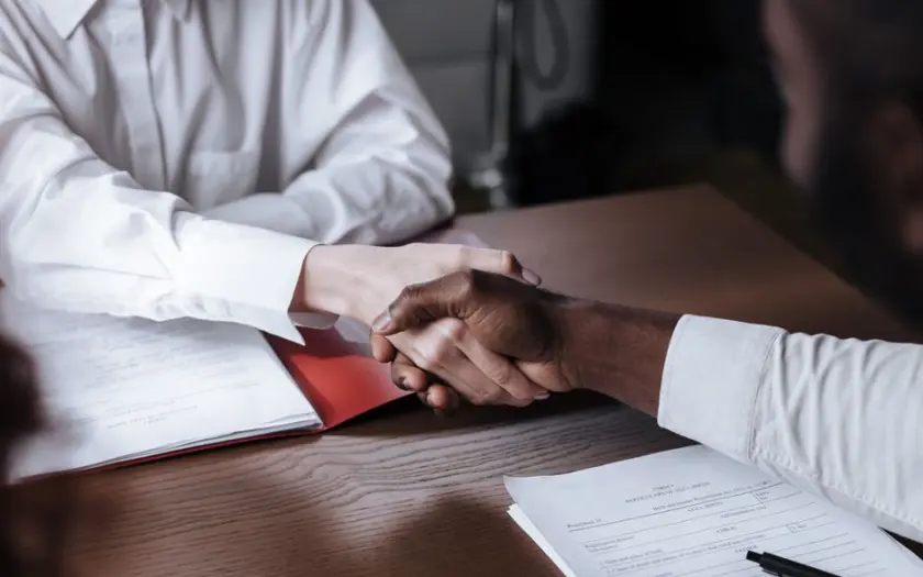 Close-up of a diverse business handshake over documents, symbolizing agreement and collaboration.