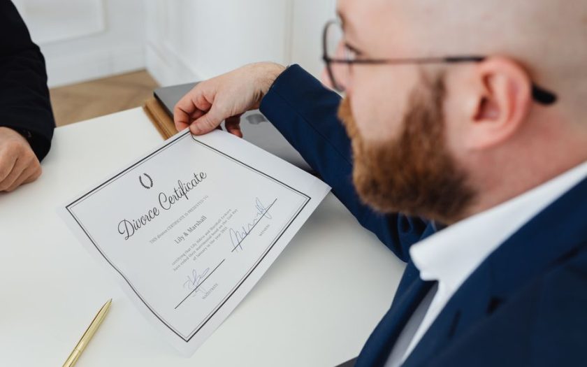 A man holding a divorce certificate in a formal office environment.