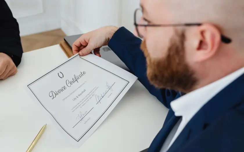 A man holding a divorce certificate in a formal office environment.