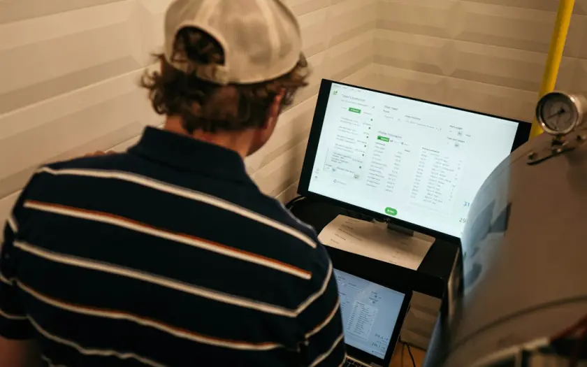 man in white and black striped polo shirt in front of monitor
